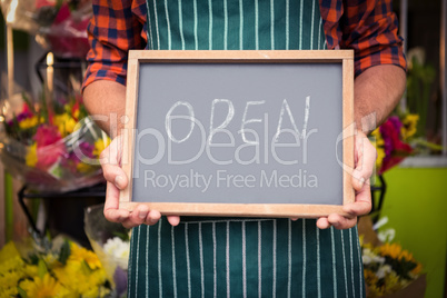 Male florist holding open sign on slate at his flower shop Male florist holding open sign on slate at his flower shop