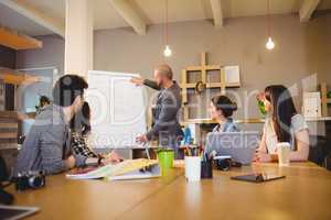 Male graphic designer discussing chart on white board with cowor