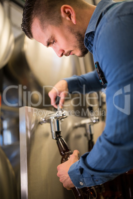 Brewer filling beer in bottle