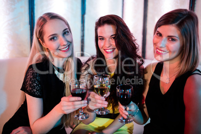 Smiling friends sitting together and having wine