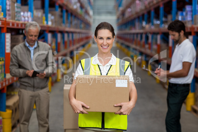 Focus on worker is holding cardboard box and smiling