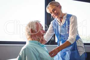 Nurse using stethoscope to take care of a senior man