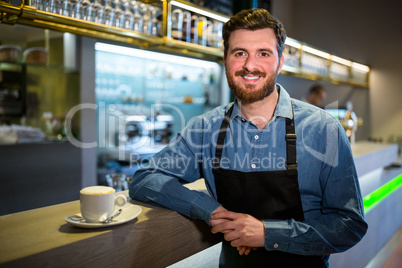 Waiter standing at the counter with cup of coffee