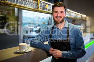 Waiter standing at the counter with cup of coffee