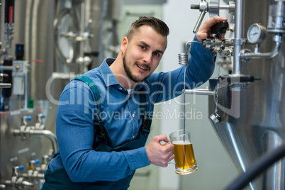 Brewer testing beer from tank