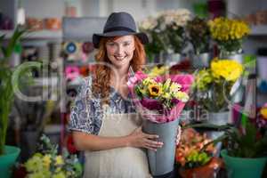 Happy female florist holding flower vase