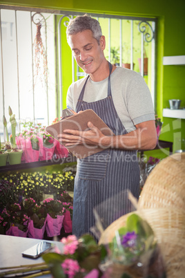 Male florist writing on clipboard