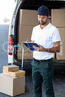 Portrait of delivery man is writing something on a clipboard
