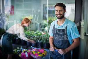 Male florist standing while female florist working in the backgr