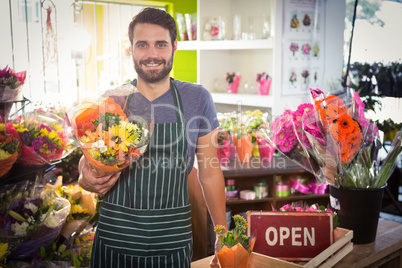Male florist holding bouquet of flower at his flower shop