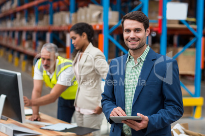 Focus on manager is smiling and holding a tablet in front of his