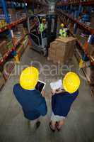 High angle view of manager wearing hard hat and looking workers