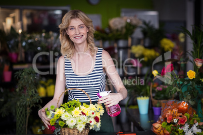 Female florists spraying water on flowers in flower shop