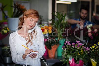 Female florist taking an order on telephone