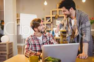 Graphic designer using laptop with his coworker