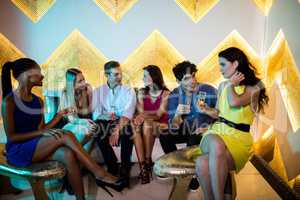 Group of smiling friends interacting while having a glass of cha