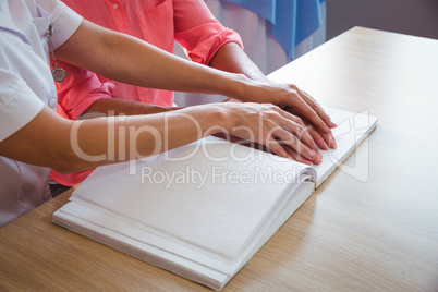 Nurse helping senior woman with braille