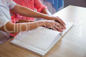 Nurse helping senior woman with braille