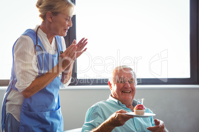 Nurse and senior man celebrating birthday with muffin