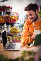 Male florist checking order in laptop