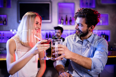 Smiling friends toasting cocktail and beer glass at bar counter