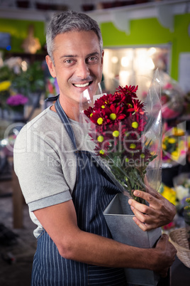 Male florist holding bunch of red sunflower in vase