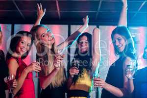 Smiling friends holding glass of champagne while dancing