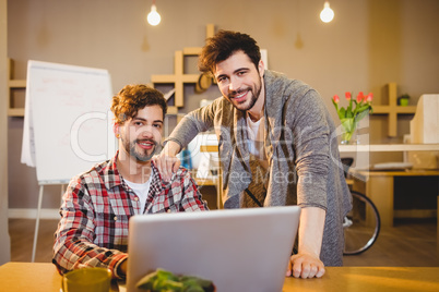 Graphic designer using laptop with his coworker