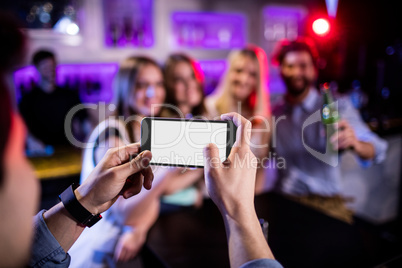 Man taking photograph of his friends with mobile phone
