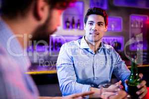 Friends interacting with each other at bar counter while having