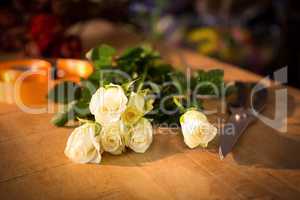 Bunch of roses with shears and poly ribbon on the wooden table