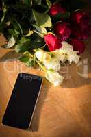 Yellow and red roses with smartphone on the wooden table