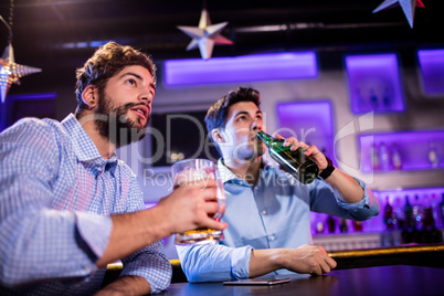 Friends sitting at bar counter and having beer