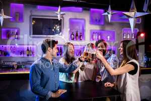 Group of friends toasting beer glasses at bar counter