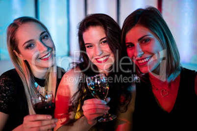 Smiling friends sitting together and having wine