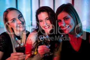 Smiling friends sitting together and having wine