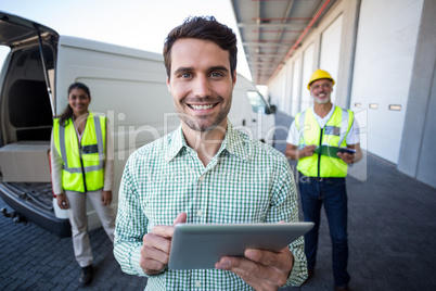 Focus of manager is holding a tablet in front of his colleagues