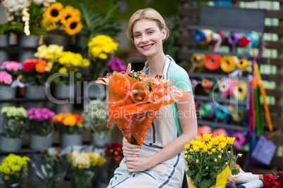 Happy female florist holding flower bouquet