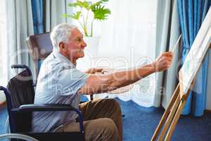Senior man using brush and easel