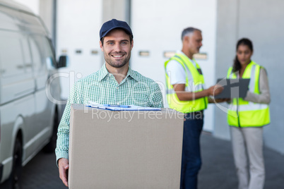 Focus of delivery man is holding a cardboard box and smiling to