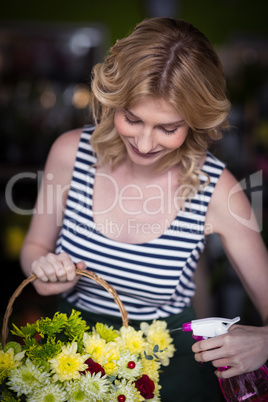 Female florists spraying water on flowers in flower shop