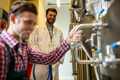 Maintenance workers examining brewery machine
