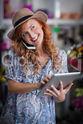 Female florist talking on mobile phone while using digital table