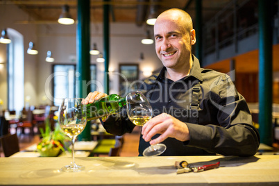 Waiter pouring white wine into glass