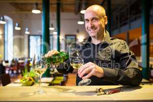 Waiter pouring white wine into glass