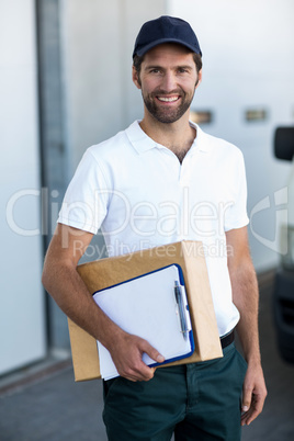 Portrait of delivery man is holding cardboard box and posing