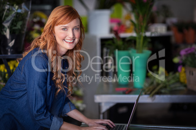 Smiling florist using laptop in flower shop