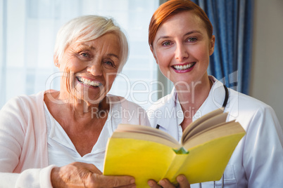 Nurse and senior woman reading book