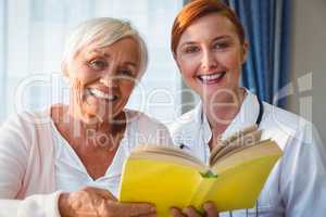 Nurse and senior woman reading book