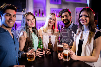 Group of friends holding beer bottle and beer glass at bar count